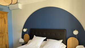 Een slaapkamer met een groot bed, een houten garderobe en een wandplank.