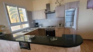 A kitchen with a central island, built-in oven, and stainless steel appliances. - Vacation apartment in Tunisia (quiet location) (CHATT MERIAM)