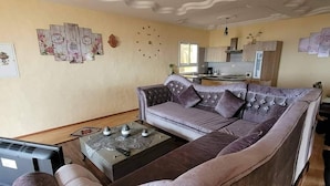 A living room with a large sofa, a coffee table, and a television. - Vacation apartment in Tunisia (quiet location) (CHATT MERIAM)