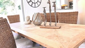 A dining area with wicker furniture, a decorative metal clock, and a woven basket. - Villa Philia near beaches, pool heated, 4 bedrooms with air conditionning (Cavalaire-Sur-Mer)