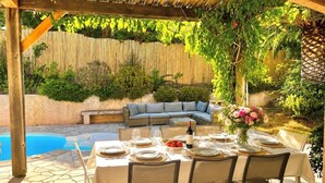 An outdoor patio with a pool, a dining table set for four, and a sofa. - Villa Philia near beaches, pool heated, 4 bedrooms with air conditionning (Cavalaire-Sur-Mer)