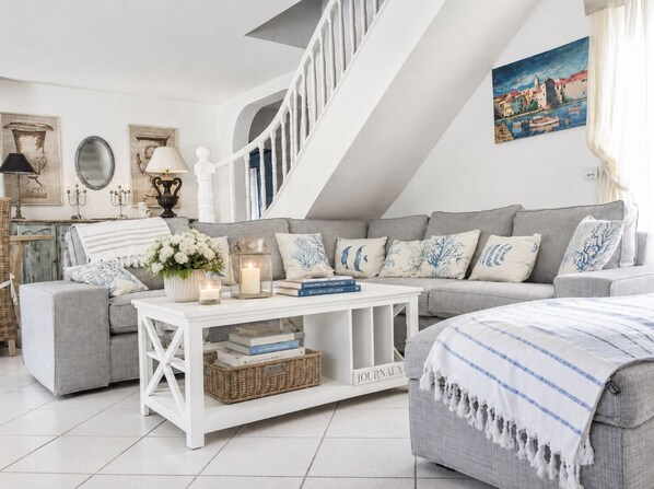 Ein gemütliches Wohnzimmer mit einem grauen Sofa, einem weißen Couchtisch und einer Treppe.