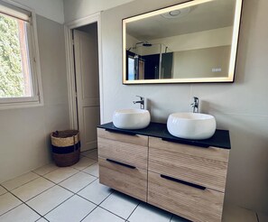 Un bagno con due lavabi bianchi, uno specchio e un armadietto in legno.