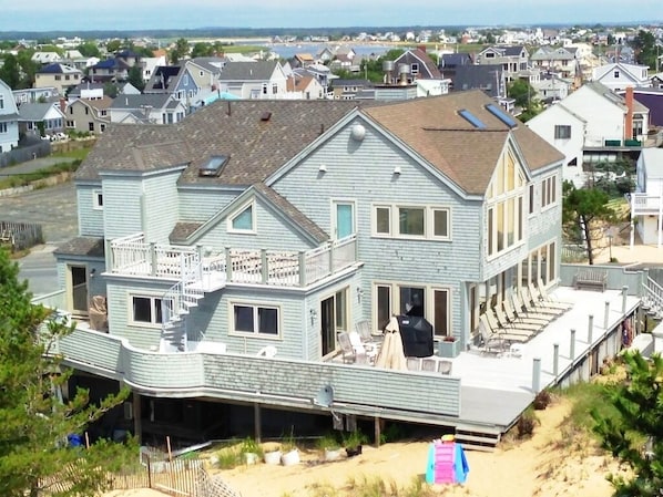 Une grande maison bleu clair à deux étages, dotée d’un balcon, d’une terrasse couverte et offrant une vue sur le quartier environnant.