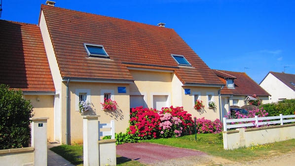 Una hilera de casas con tejados rojos, contraventanas blancas y balcones con flores.