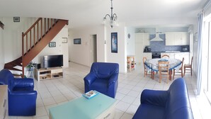 Ein Wohnzimmer mit Fernseher, blauen Sofas, einem Couchtisch und einer Treppe.