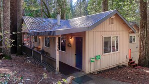 Une petite cabane à un seul étage, avec un toit en métal, une véranda et une porte.