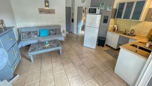 Un espacio habitable compacto con sofá, una mesita de centro, kitchenette y microondas.