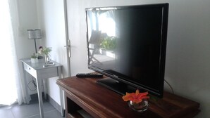 Un televisor sobre un soporte de madera con un control remoto y un florero.