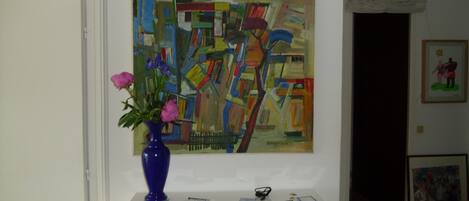 Une pièce comprenant une console blanche sur laquelle sont disposés un vase de fleurs, un tableau et quelques objets personnels.