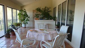 Un comedor con una mesa redonda, sillas blancas y plantas en macetas.