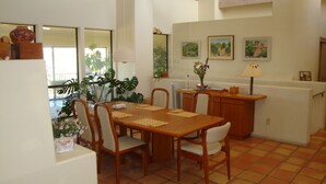 Comedor con mesa y sillas de madera, mostrador de cocina y vista al exterior.