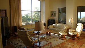 Una sala de estar con sofá, sillones, una mesa de centro y televisor.
