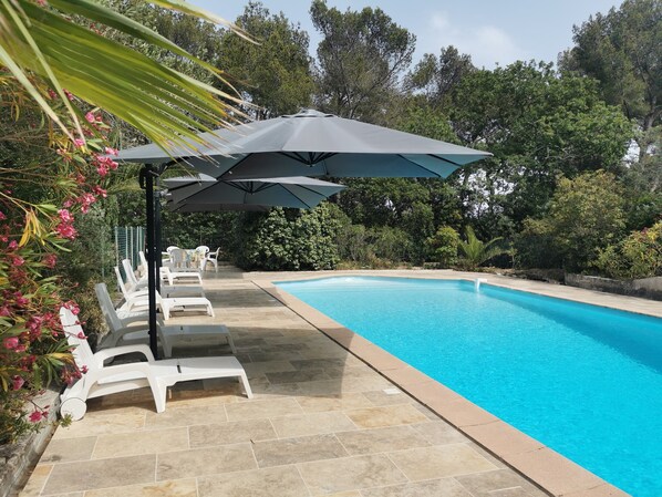 A swimming pool with white lounge chairs and a large umbrella.