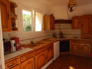 A kitchen with wooden cabinets, a sink, a stove, and a dishwasher. - LARGE VILLA 12 PERS. 5 mn from the beaches. LARGE SWIMMING POOL AND 2000m2 LAND. (Six-Fours-Les-Plages)
