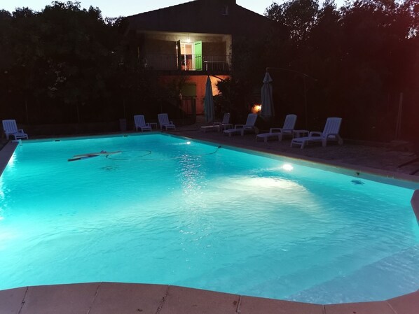 En swimmingpool med ett klart, blått vatten och vita solstolar runt omkring.