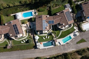 Vista aérea de una zona residencial con varias casas, cada una con piscina, paneles solares y césped cuidado.