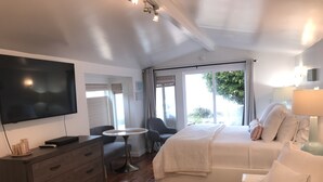 A bedroom with a bed, bedside table, TV, and a small round table.