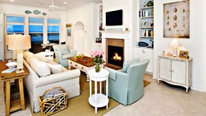 Ein Wohnzimmer mit Kamin, einem darüber hängenden Fernseher und einem Bücherregal mit Büchern und Dekoration.