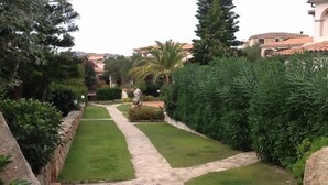 Ein gepflegter Garten mit einem Steinweg, ordentlich gestutztem Gras und verschiedenen Sträuchern.