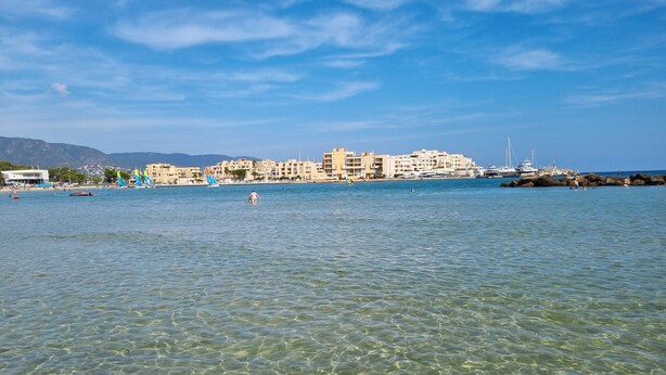 A coastal town with clear waters, buildings, and boats.