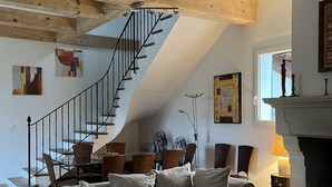 Una sala de estar con una escalera de madera, chimenea y un conjunto de sofás.