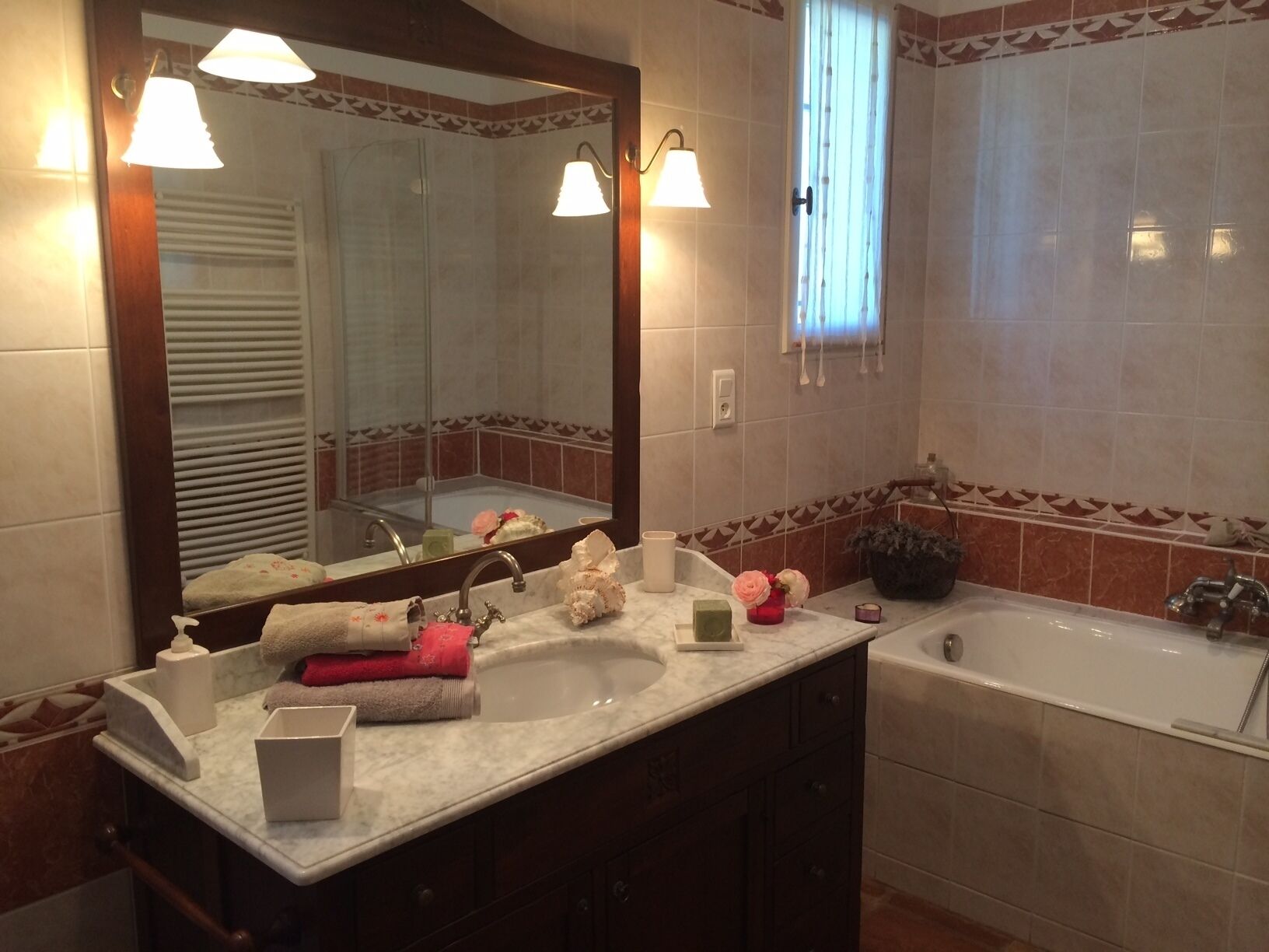 A bathroom with a large mirror, two sinks, a bathtub, and decorative items on the counter.