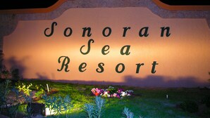 A sign for Sonoran Sea Resort with a stone arch and a logo above the name.