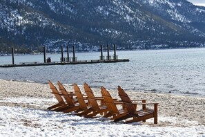 A beach with wooden chairs and a dock extending into a lake, surrounded by snow-covered mountains. - Gorgeous, McCloud Condo, Short Walk to Beaches - Owner Managed TLT#W-4564 (Incline Village)