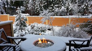 Ett utomhusområde med sittplatser, täckt av snö, och en eldstad.
