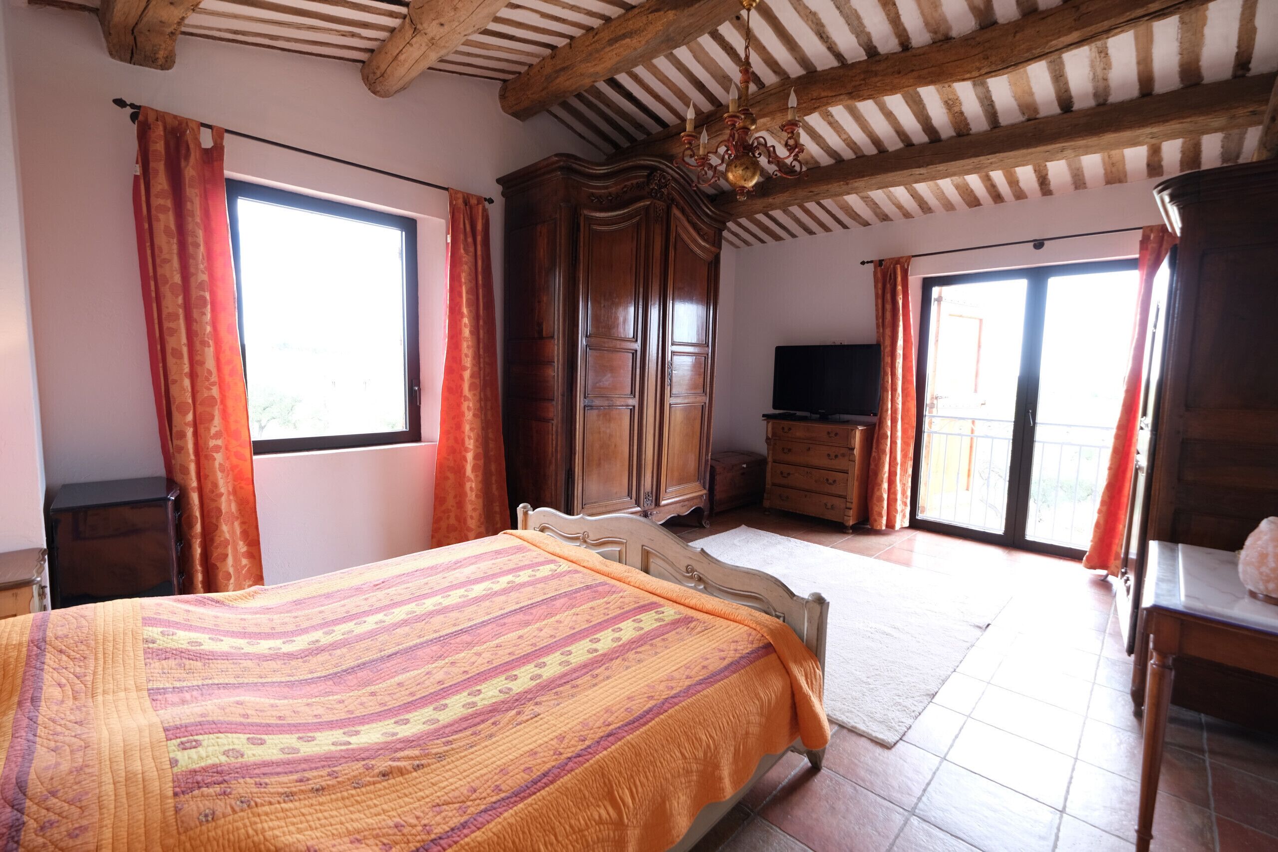 Een slaapkamer met een groot bed, een houten kledingkast en een televisie.