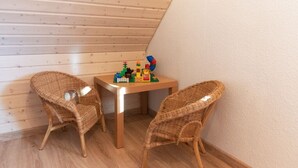 Ein Eckzimmer mit zwei Korbstühlen, einem kleinen Holztisch und einem Spielzeugset auf dem Tisch.