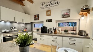 Eine moderne Küche mit weißen Schränken, Edelstahlgeräten und einer Holzbalkendecke.