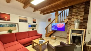 Ein Wohnzimmer mit rotem Sofa, Couchtisch aus Holz und einem Fernseher an einer Ziegelwand.