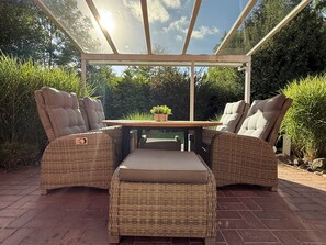 A covered outdoor seating area with wicker furniture and a table.