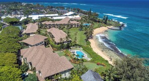 An aerial view of a resort with multiple buildings, a swimming pool, and a beach.