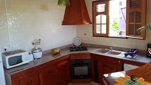 Een keuken met houten kastjes, een magnetron, een fornuis en een spoelbak.