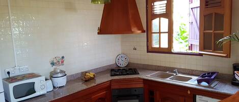Une cuisine avec des meubles de rangement en bois, un four à micro-ondes, une cuisinière et un évier.