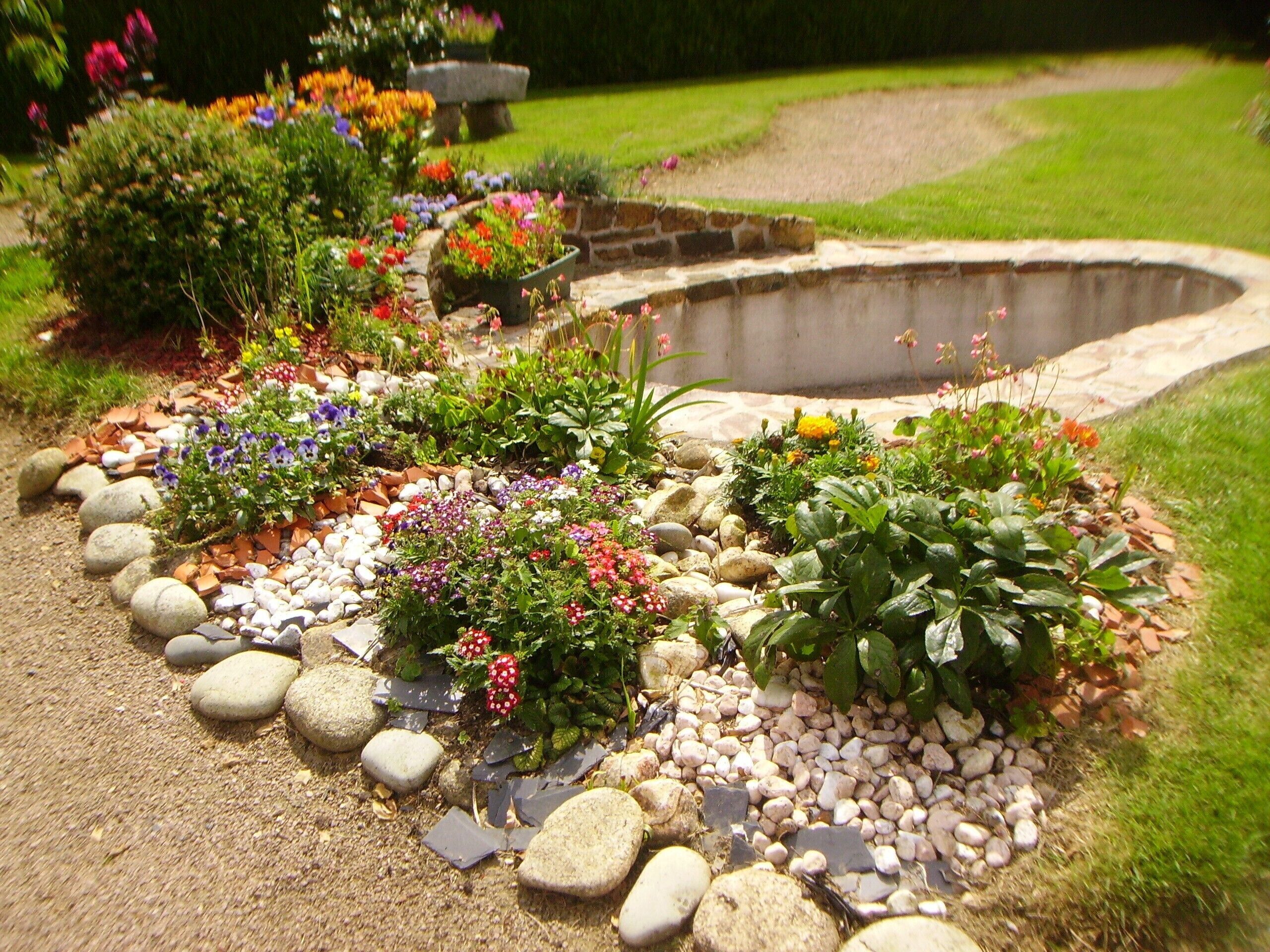 A garden with a variety of plants and a stone water feature.