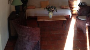 Una sala de estar acogedora con un sofá, una mesa de centro y dos sillones. Hay una lámpara en una mesita auxiliar, una planta en maceta y un cuadro en la pared.