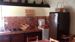 Una cocina con salpicadero de azulejos, un refrigerador, una estufa y una mesa de comedor con sillas.