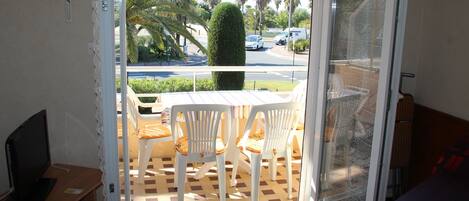 A balcony with a checkered floor, white chairs, and a table.