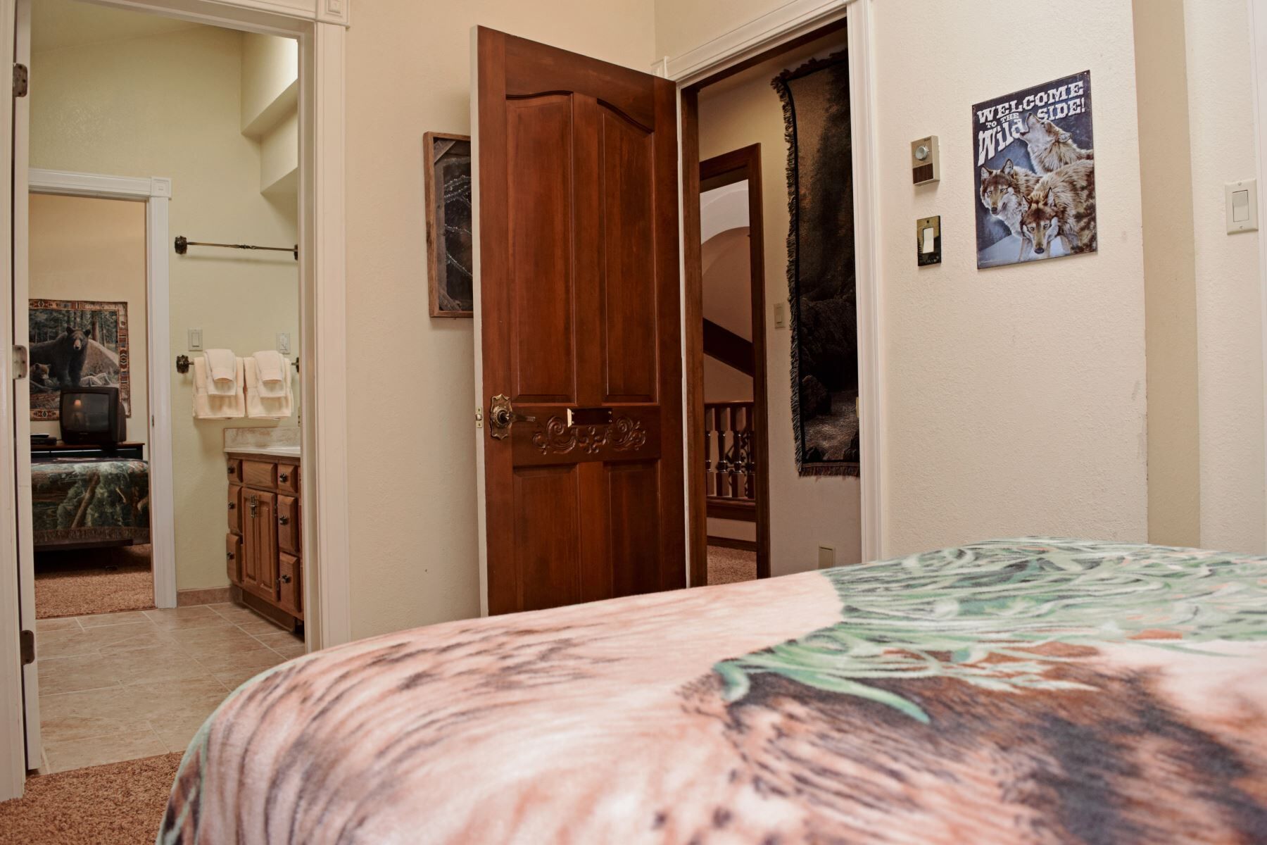 Un dormitorio con una cama, una puerta de madera, un cartel y un baño visible a través de una puerta abierta.