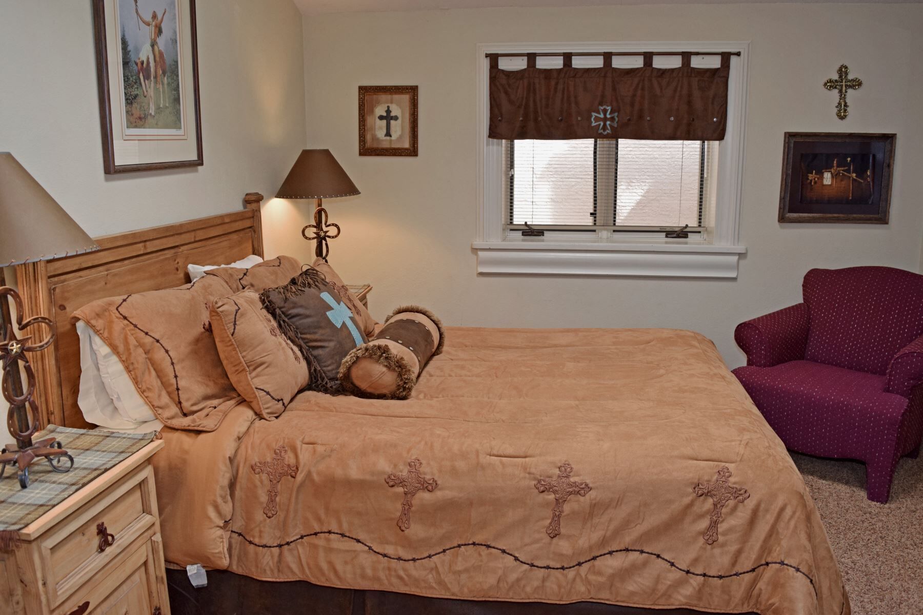 A bedroom with a bed, a nightstand, a lamp, a window with curtains, and a chair.