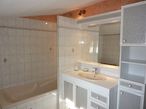 Une salle de bain avec une baignoire, un lavabo et un grand miroir.