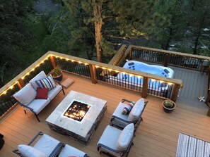 A deck with outdoor seating, a fire pit, and a hot tub.
