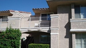 Un bâtiment à deux étages, doté d’une façade en pierre, d’un balcon avec des balustrades blanches et d’une petite entrée en forme d’arc.