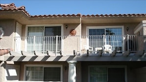 Un bâtiment à deux étages doté d’un balcon, d’une terrasse couverte avec des chaises et d’une colonne en pierre.
