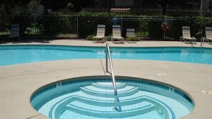 Une piscine dotée d’un élément décoratif central, entourée de chaises longues et d’une clôture.