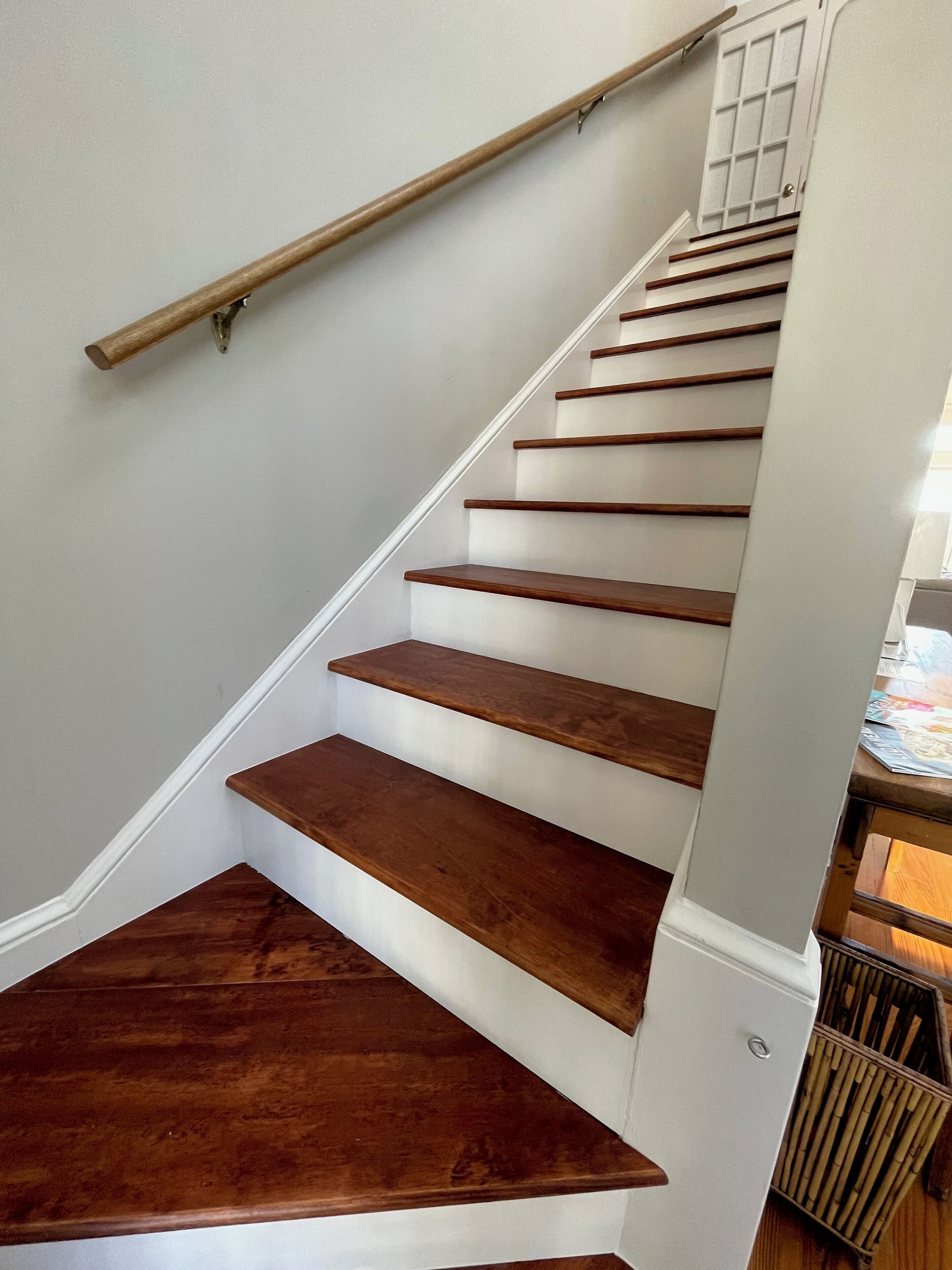 Una escalera con escalones de madera y una pared blanca.